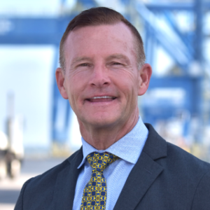 A professional headshot of Phillip Wells, General Counsel of North Carolina Ports. Container Cranes are in the background.
